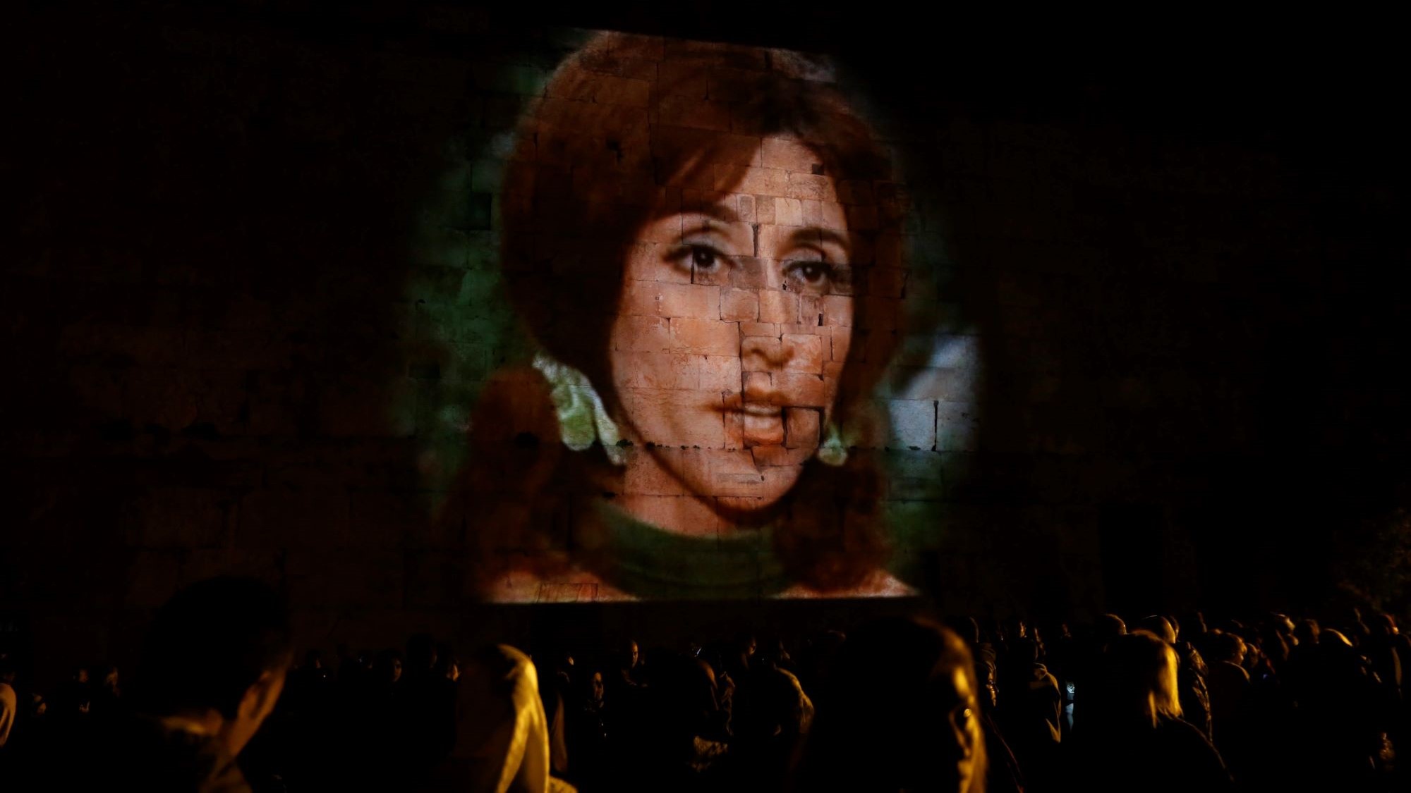 Fairuz projected in Baalbek, 2016. (Photo: picture alliance/ EPA/N. Mounzer) The face of a woman is projected onto a wall made of large stone blocks.