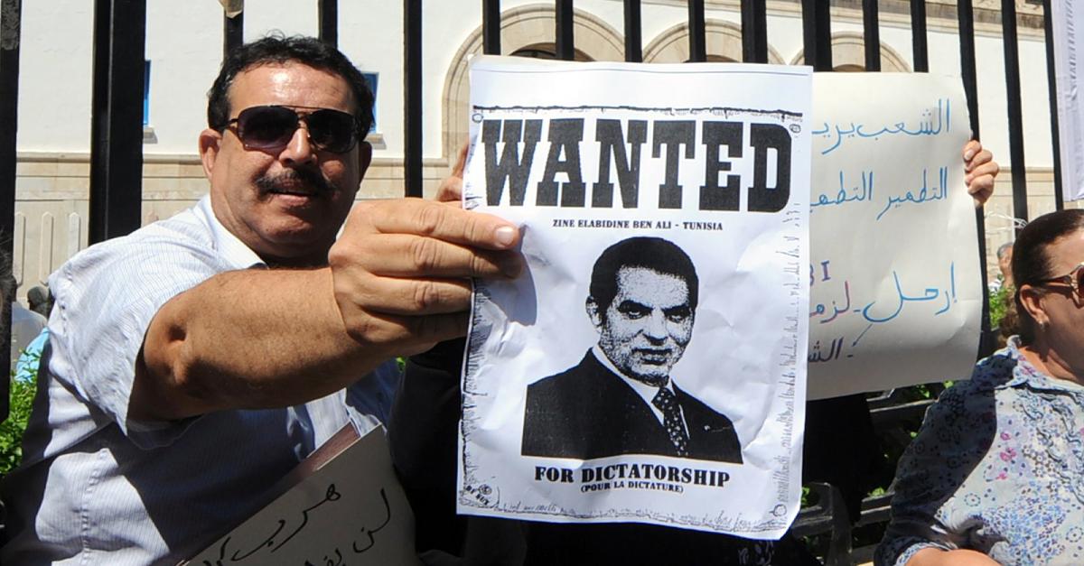 تونسي يحمل لافته مكتوب عليها بالإنكليزية " مطلوب: بن علي - تونس". Foto: AFP تونسي يحمل لافته مكتوب عليها بالإنكليزية " مطلوب: بن علي - تونس". Foto: AFP