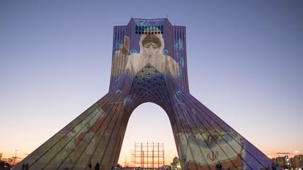 The portrait of a nurse in a protective suit is projected onto the Azadi monument in Tehran. Photo: Morteza Nikoubazl/NurPhoto The portrait of a nurse in a protective suit is projected onto the Azadi monument in Tehran.