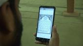 A man reads the Qur'an on a smartphone.